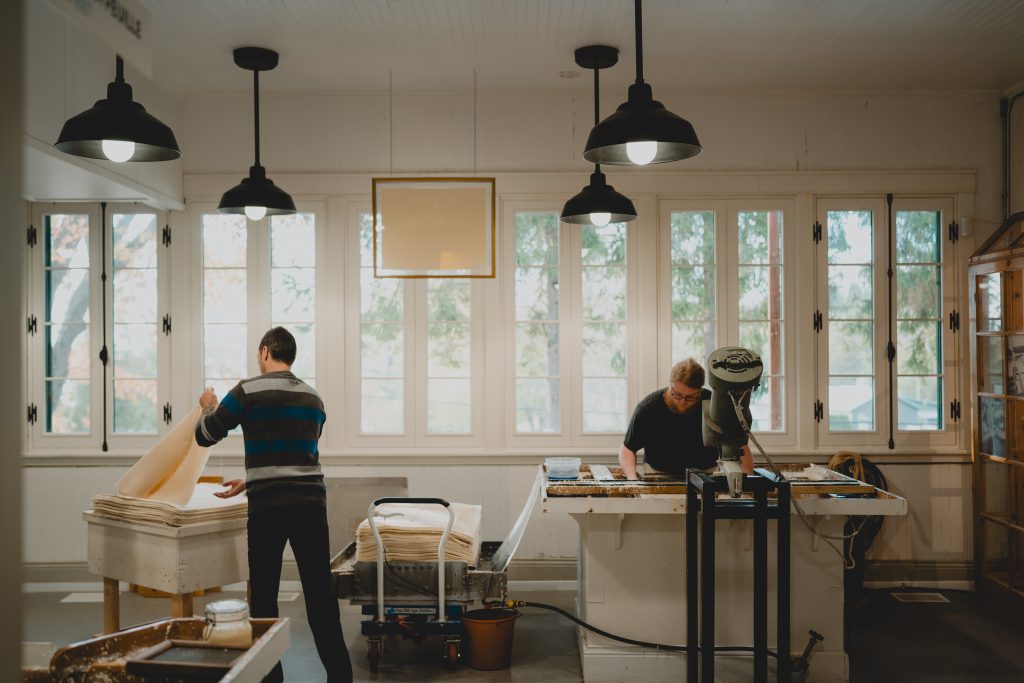 Artisans papetiers à l'ouvrage dans l'atelier de fabrication de la Papeterie Saint-Gilles