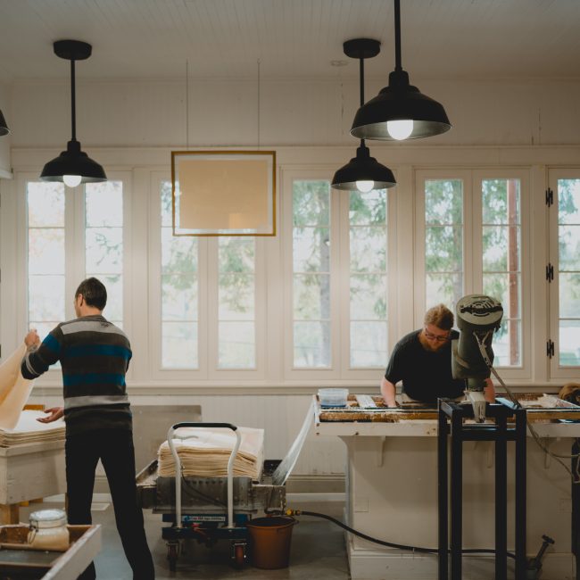 Artisans papetiers à l'ouvrage dans l'atelier de fabrication de la Papeterie Saint-Gilles